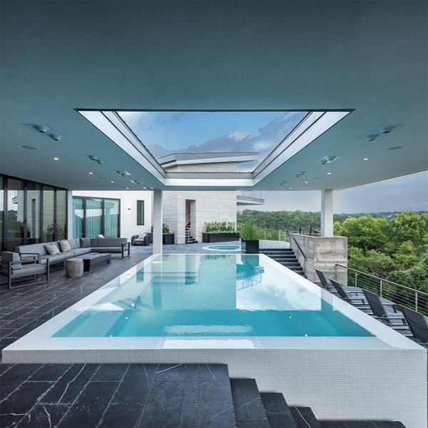 Piscine à débordement blanche, par Design Ecology, contrastant avec le noir de son environnement et encadrée par l'espace creux du plafond
