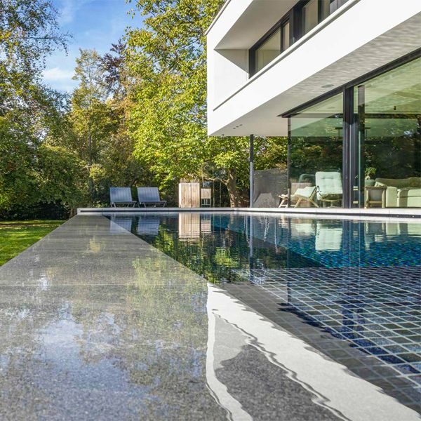 détail du revêtement en carrelage et pierre d'une piscine à débordement, par DC Pools