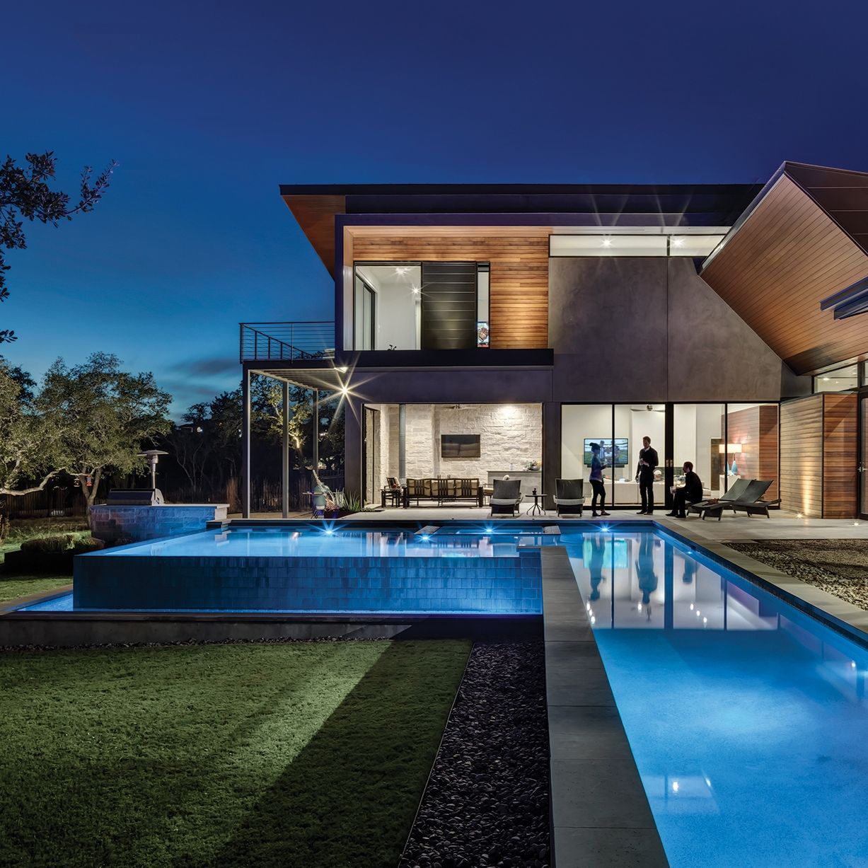 Piscine à débordement au design en forme de L, avec couloir de nage, idéale pour nager, éclairée la nuit, dans un projet de MF Architecture