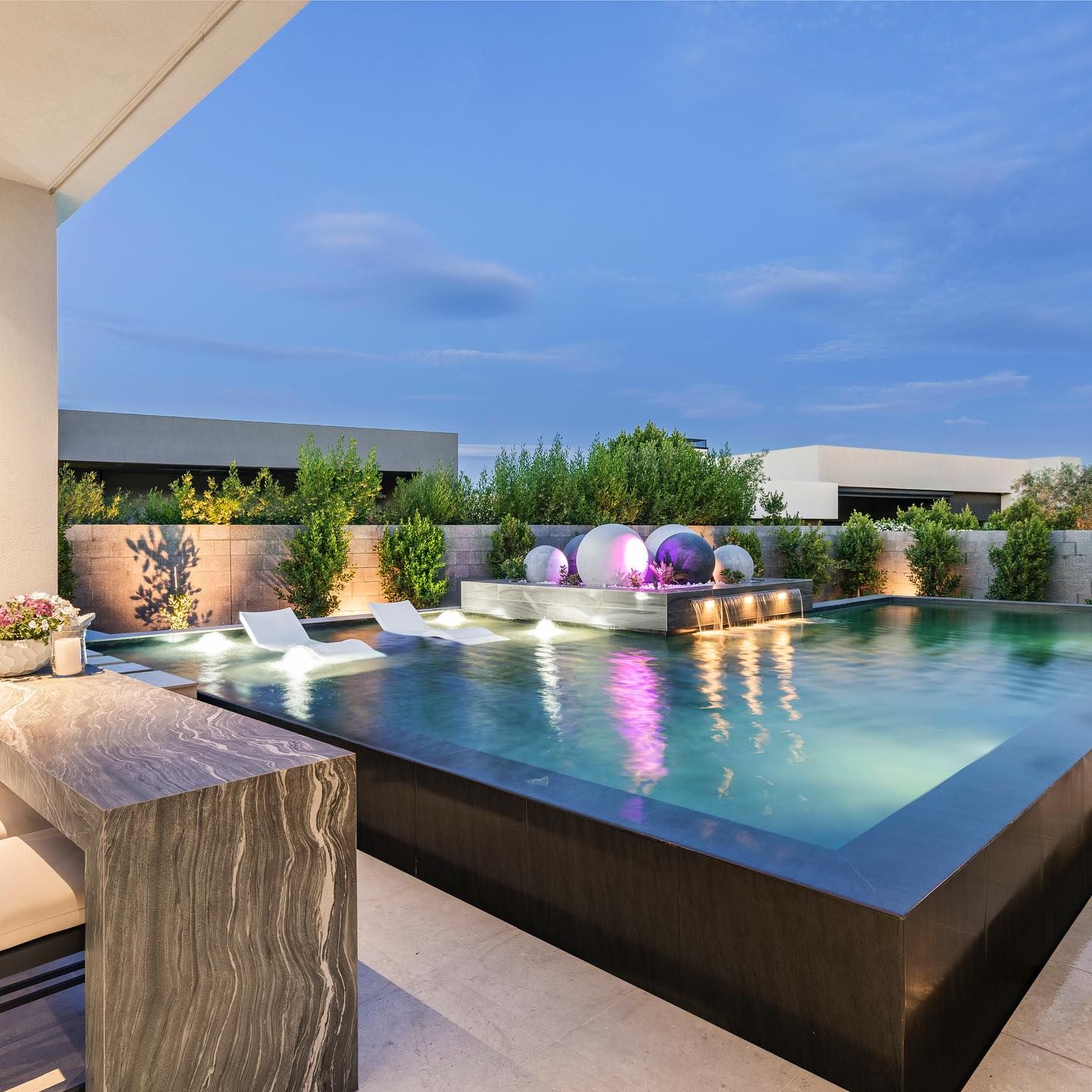 Élégante piscine à débordement par Lavender Landscape Design, éclairée la nuit