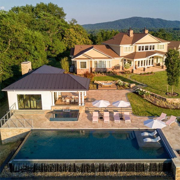 Vue drone d'une piscine à débordement avec spa à débordement indépendant, dans un projet par Colao & Peter, sur un grand terrain avec une maison de conception classique