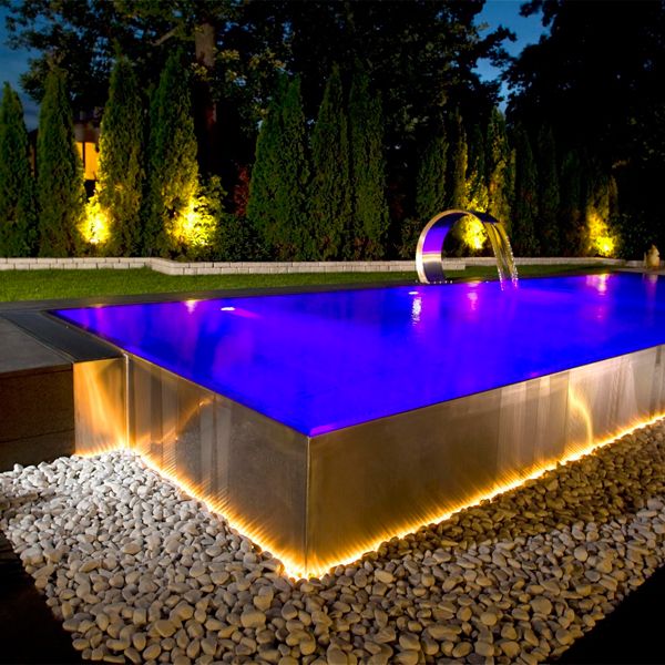 piscine inox à débordement, cascade également en acier, par Berndorf Pools, éclairée la nuit dans un jardin privé