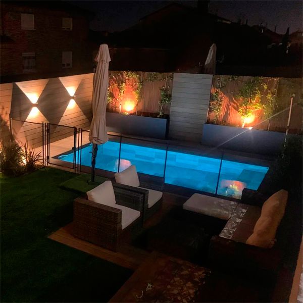 Piscine privée au design classique et revêtement en grès cérame, entourée d'une terrasse en bois synthétique, dans un projet Piscinas Los Hermanos, at night