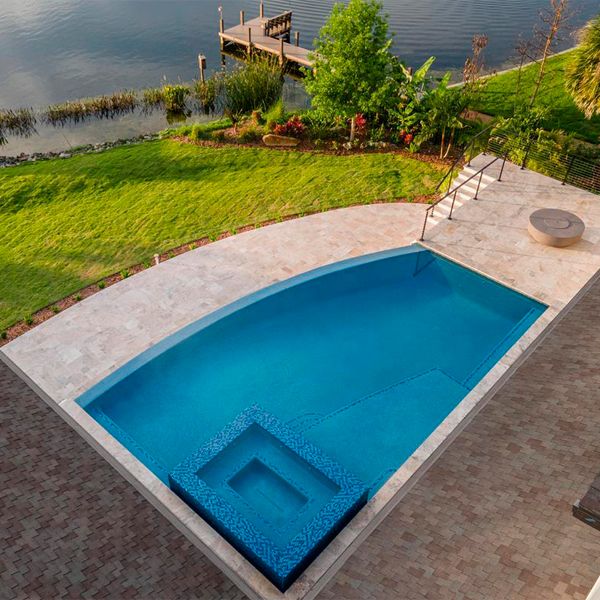 vue drone d´une piscine à débordement sur mesure avec spa intégré, par All Custom Pools, à côté du lac