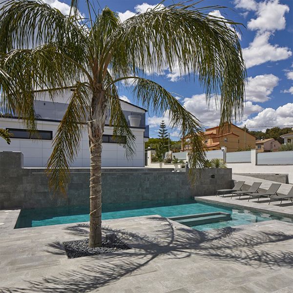 Piscine privée sur mesure par Pool Jump, dans un espace monochrome contrastant avec les palmiers