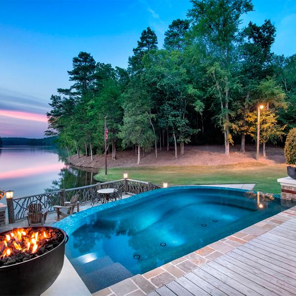 Mini piscine spa à débordement sur mesure, par Crystal Pools, dans une maison au bord du lac, au coucher du soleil