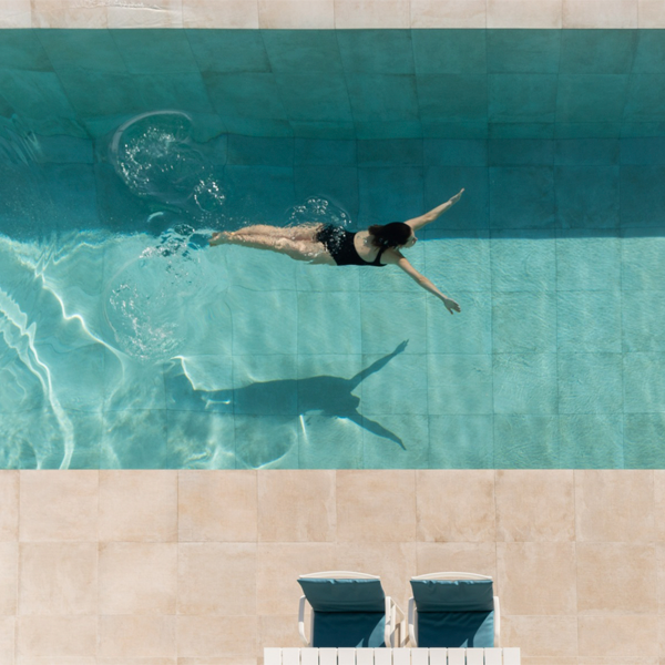 vue de drone d'une femme nageant dans une piscine à débordement par Angel Fito Estudio