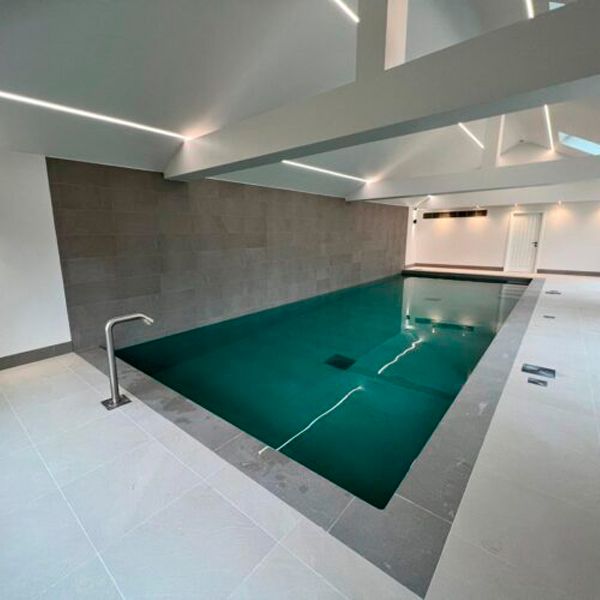 Piscine intérieure au design rectangulaire classique, de Blue Cube Pools, avec canon à eau, équipement de nage à contre-courant et couleur contrastée avec l'espace du sous-sol