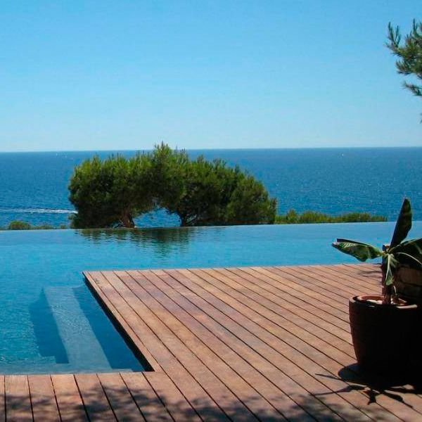 vue mer depuis une piscine à débordement entourée d'une terrasse en bois, par Jacques Hugony