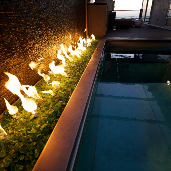 Mini piscine inox avec parois vitrées, à côté d'un espace avec feu, dans un projet d´une maison moderne par David Hertz Architects FAIA, au coucher du soleil