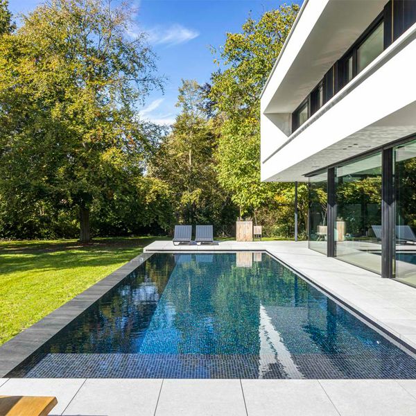 piscine à débordement minimaliste par DC Pools, dans un projet de piscine et de jardin dans une maison au design moderne