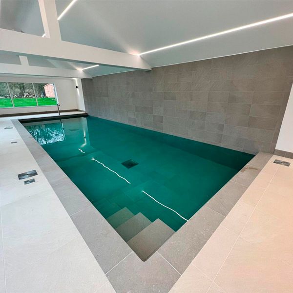 Piscine intérieure au design rectangulaire classique, de Blue Cube Pools, avec un canon à eau et une couleur contrastante avec l'espace du sous-sol