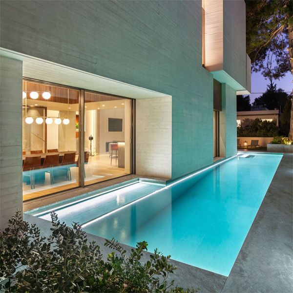 piscine moderne et minimaliste la nuit, dans un projet par Divercity Architects