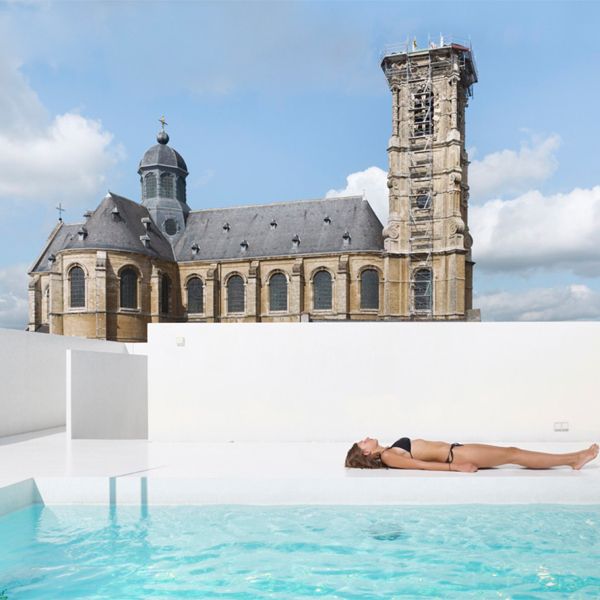 femme prenant un bain de soleil au bord d'une piscine panoramique blanche dans un rooftop, dans un projet par dmvA Architecten