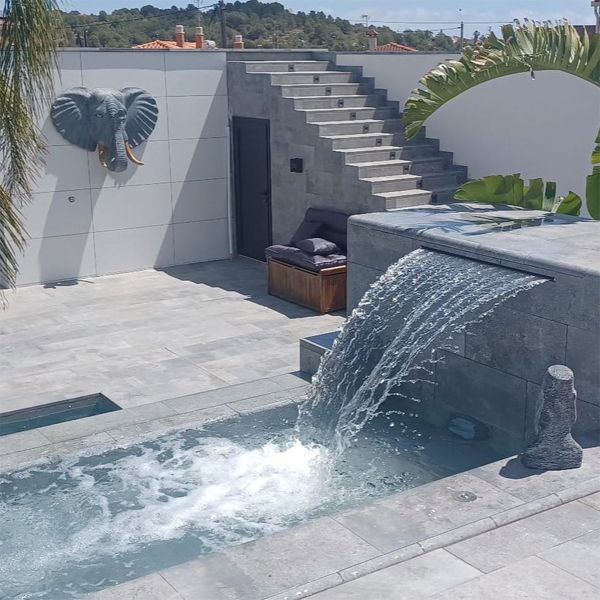 Piscine sur deux niveaux avec cascade et espace spa, by Pool Jump, dans un espace minimaliste à la décoration zen