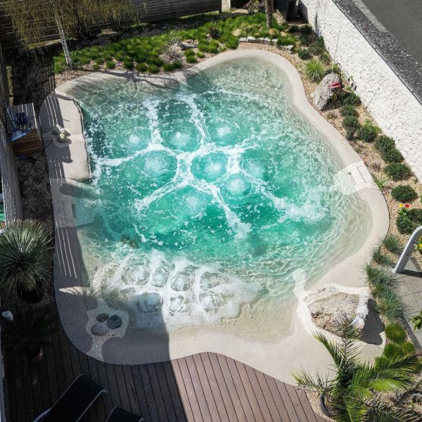 Vue drone d´une piscine naturelle Biodesign, style plage, réalisée sur mesure dans un petit jardin privé, par Gartengestaltung Sven Pfadt