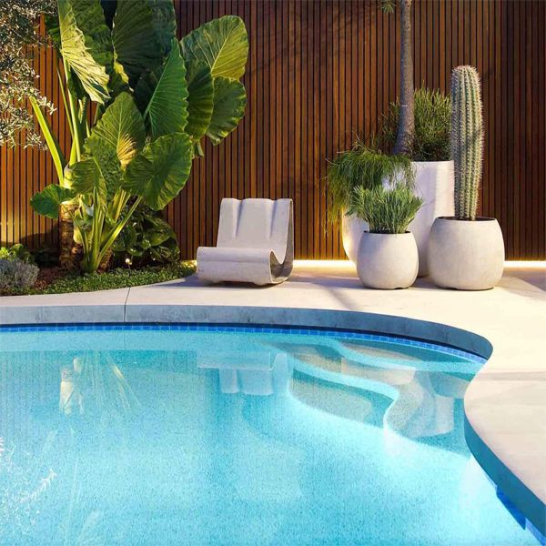 piscine privée, au design courbé, par Impressions Pools, dans un jardin moderne la nuit