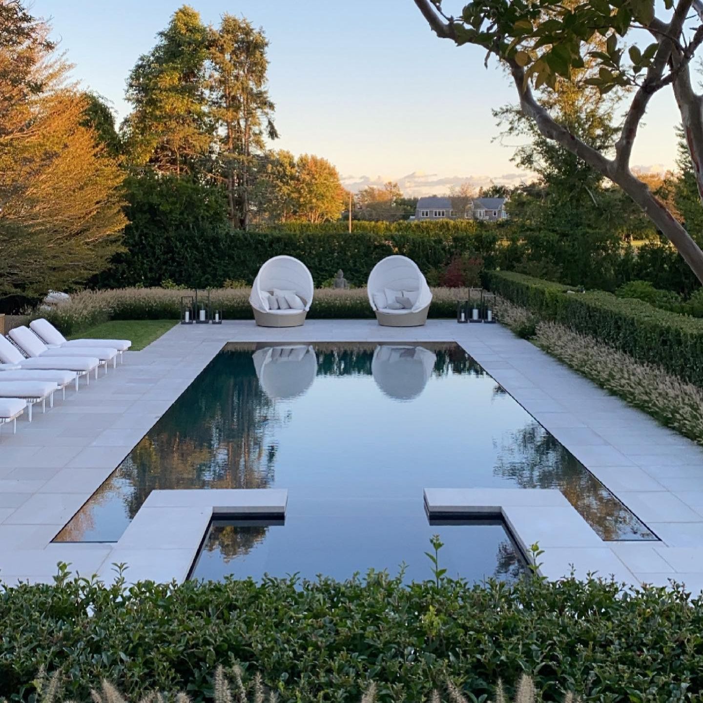 Piscine à débordement spectaculaire, effet miroir, avec spa infinity intégré, dans un élégant jardin, par LaGuardia Design, au coucher du soleil
