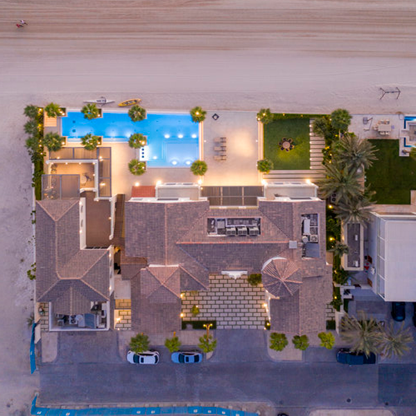 vista desde drone de piscina con palmera junto a la playa al atardecer