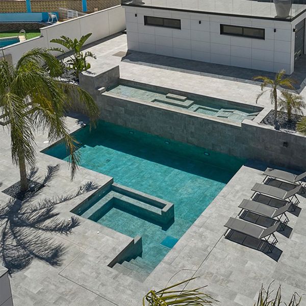 Vue drone d'une piscine unique, avec espaces spa, divisée en deux niveaux, par Pool Jump, dans un espace monochrome
