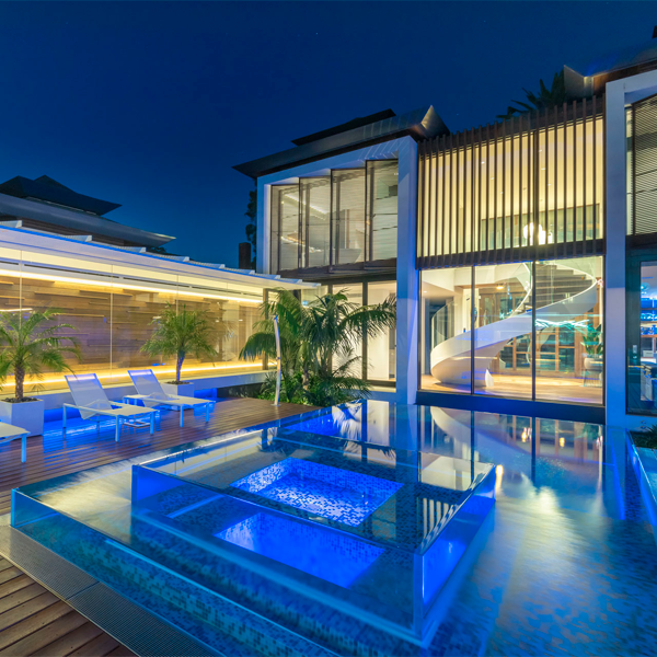 une piscine transparente unique avec spa intégré à débordement la nuit, par Pool Windows