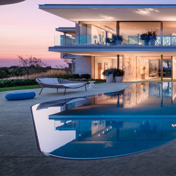 piscine unique à débordement, type miroir, dans un projet architectural moderne, futuriste et à la fois, minimaliste, par Rees Roberts, au coucher du soleil