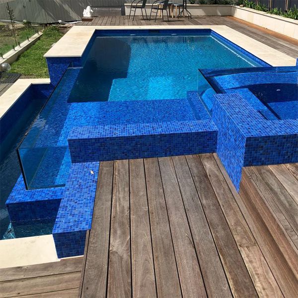 Superbe mini piscine à débordement et spa, avec un revêtement en carreaux mosaïque bleu profond et des parois vitrées, par Senator Pools, sur une terrasse en bois