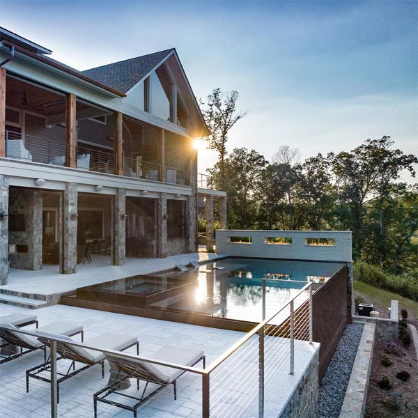 Piscine à débordement sombre, avec spa intégré, par Signature Luxury Pools, située sur une terrasse au design moderne et minimaliste, au coucher du soleil