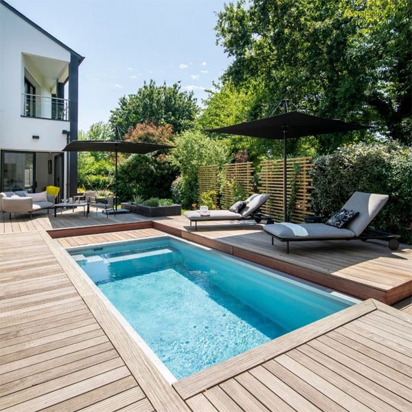 mini piscine inox, style spa de nage, dans un petit jardin avec une couverture et terrasse en bois, par Swim N Spa